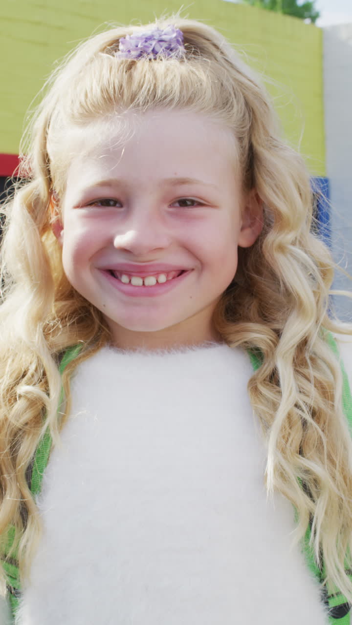 Vídeo vertical de retrato de menina escolar caucasiana feliz na escola.