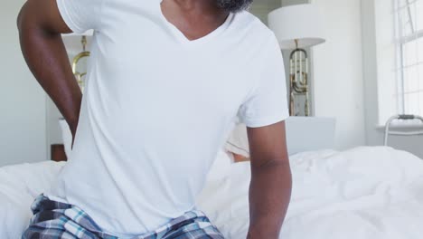 African-american-senior-in-bed-man-getting-up-with-back-pain