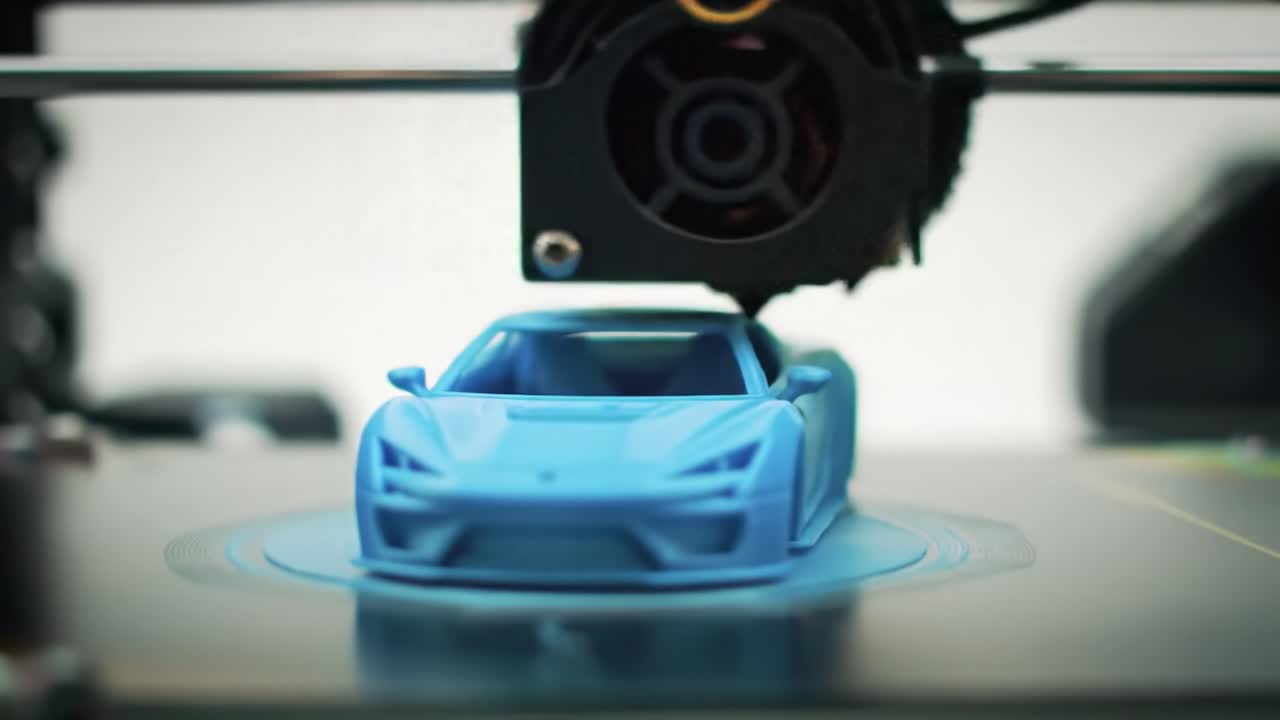 A focused look at a blue car model being created on a 3D printer in a modern workshop. The intricate design showcases advanced technology in action.
