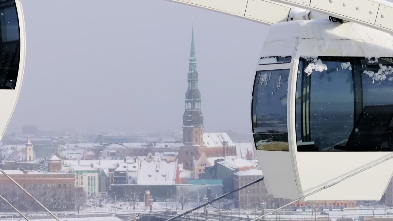 Snow-covered St. Peter’s Church rises over Riga, framed by Ferris wheel cabins