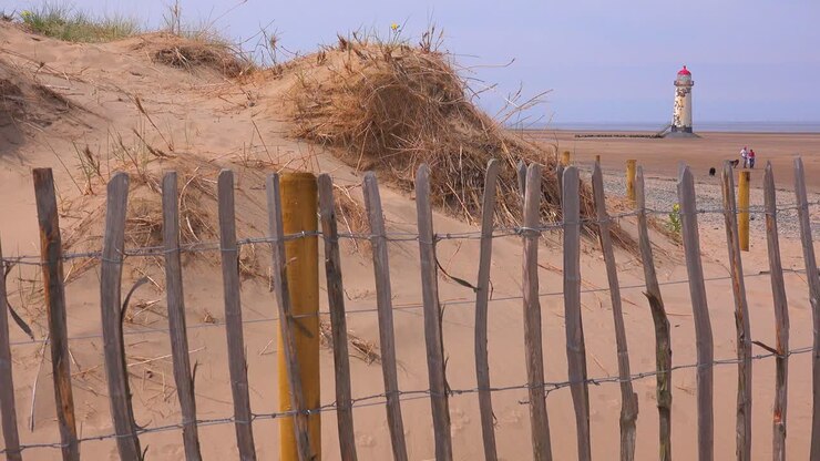 Il bellissimo faro di Point of Ayr in Galles con una staccionata consumata in primo piano.