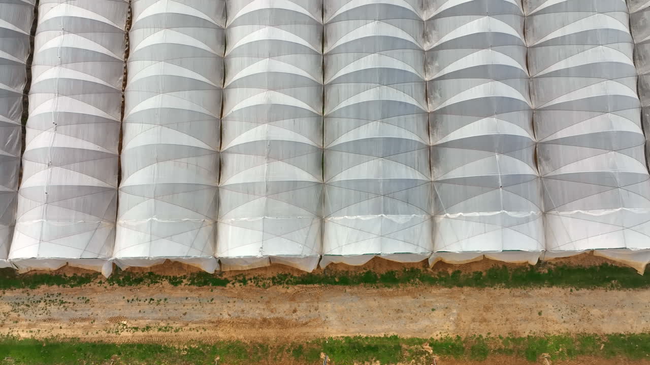 Top down aerial of greenhouse barns with white plastic. Aerial truck shot.