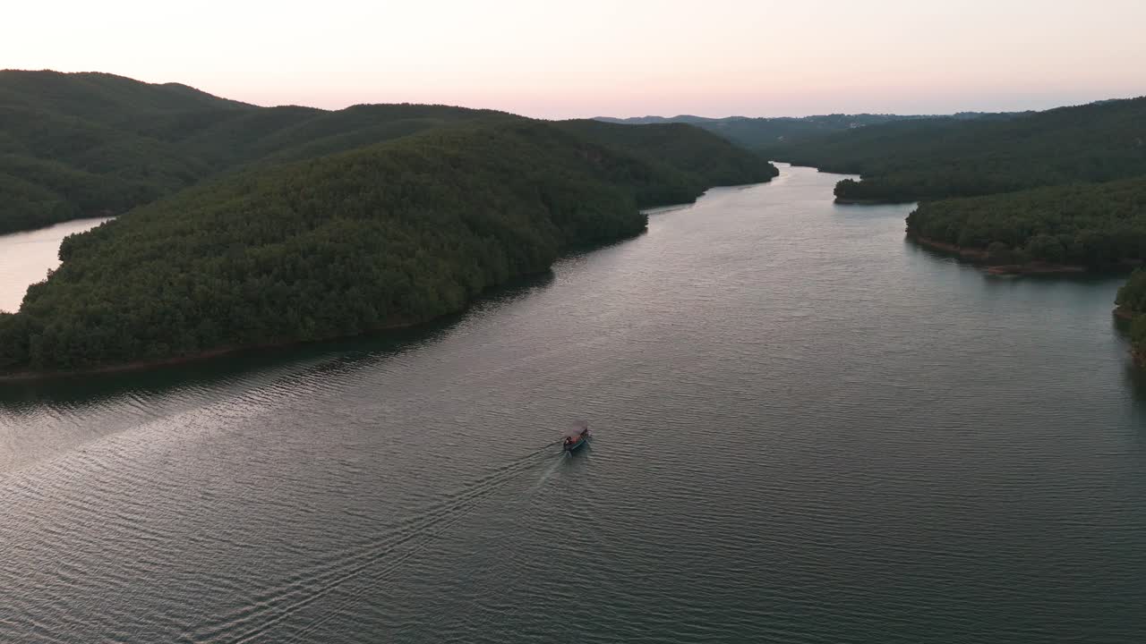 vista aérea de un pequeño barco en el río albanés y la ladera del bosque a un lado