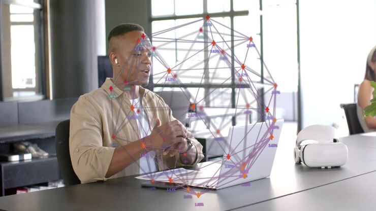 Man sitting table speaking into laptop, opening hands, pointing at wireframe globe, explaining tech