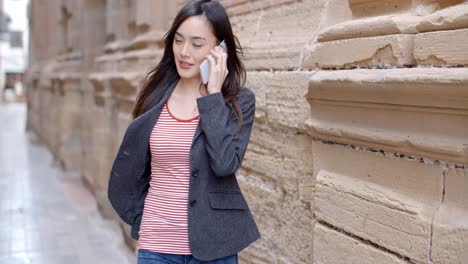 Young-woman-walking-through-town-with-her-mobile