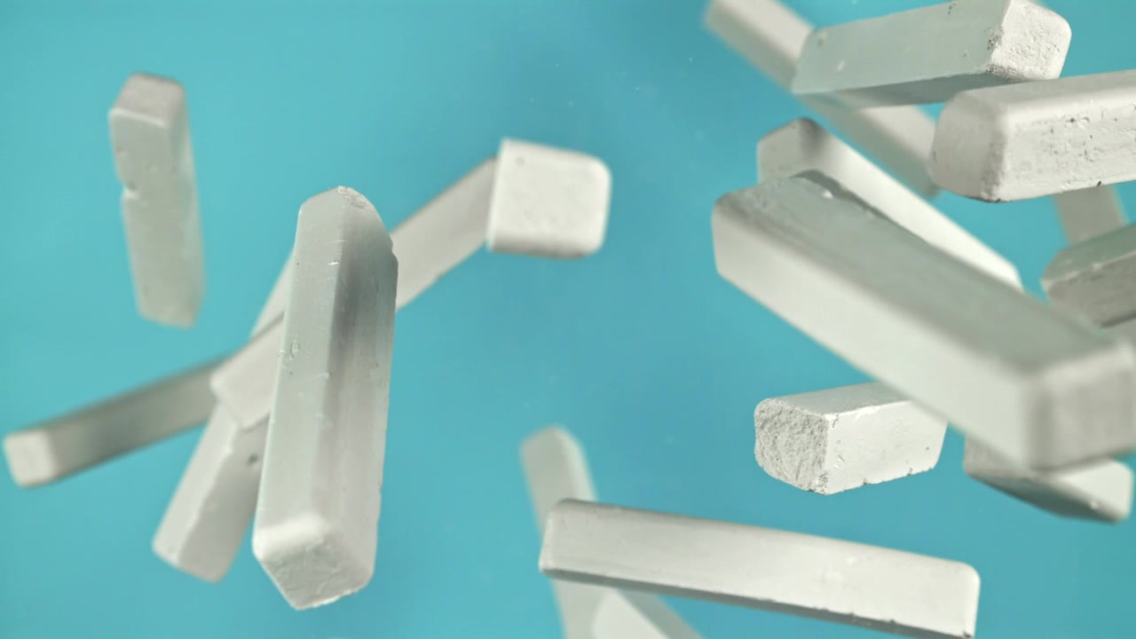 White Chalk Sticks Floating in Slow Motion Against a Blue Background