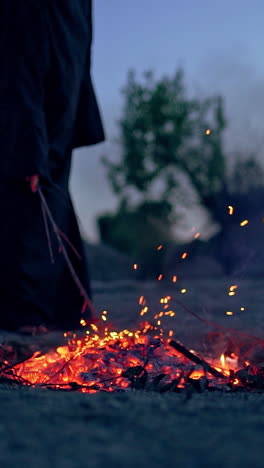 witch in black near bonfire. mystical witch walking around bonfire. vertical video