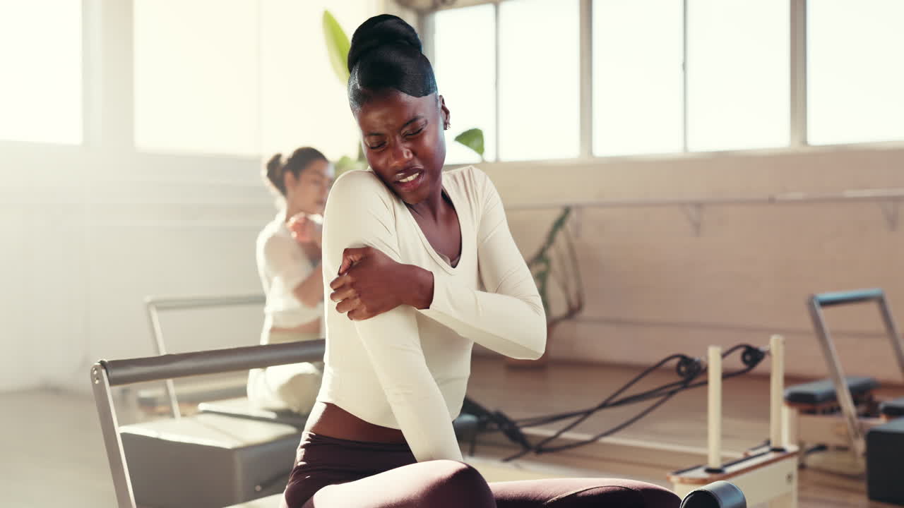 Woman experiencing arm injury during pilates workout