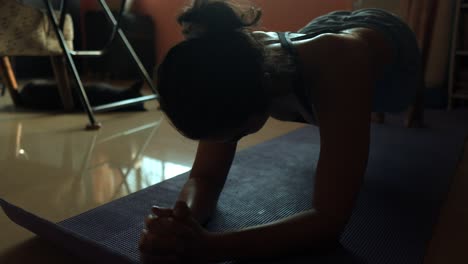 beautiful south asian woman doing plank exercises in the living room of her home