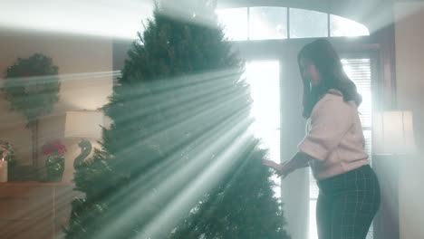 woman decorating a christmas tree bathed in light rays
