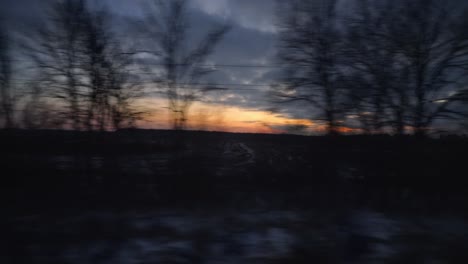 orange sunset skies train journey window pov going past silhouette of trees