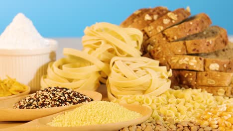 a variety of grains, pasta, and bread arranged against a bright blue backdrop, highlighting textures and colors