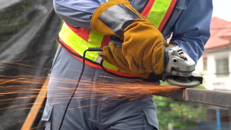 industrial technician engineer in protective cloth wear safety mask, welder man using angle grinder while working in industrial workshop. sparks during the cutting of metal by an angle grinder