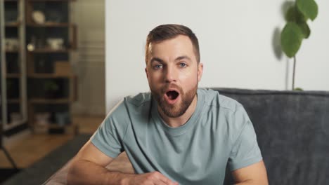 portrait of a man sitting on a sofa with emotions of surprise at what he saw