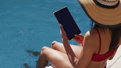 Mixed-race-woman-sitting-by-a-pool-at-home