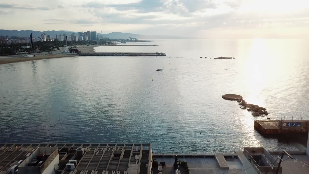 백그라운드에서 전기 보드를 타는 서퍼와 함께 일출 바르셀로나의 올림픽 항구 상공에서 공중 공개 샷