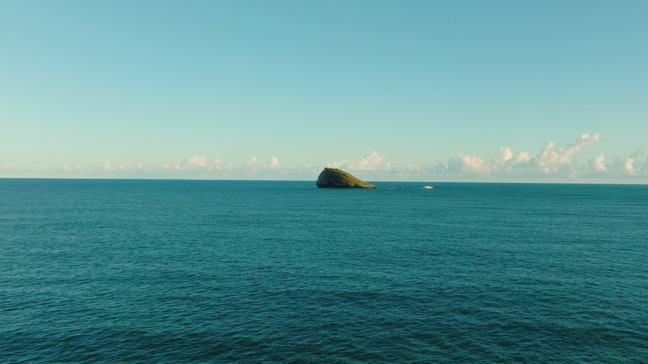 FPV drone racing fast over open sea toward a tiny uninhabited island near Guadeloupe