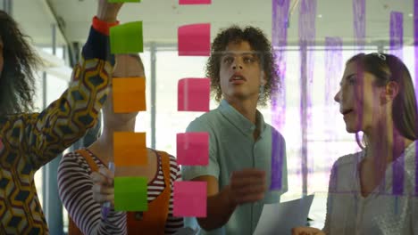 Front-view-of-young-mixed-race-business-executives-working-on-sticky-notes-in-modern-office-4k