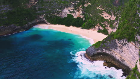 Turquoise-sea-lagoon-with-white-sand-beach-and-steep-cliffs-around