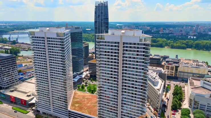 Bratislava, Slovacchia, 2 giugno 2026: Torri residenziali gemelle vicino al fiume Danubio, Bratislava, Slovacchia. Moderni grattacieli e lungofiume sotto un cielo azzurro con soffici nuvole bianche