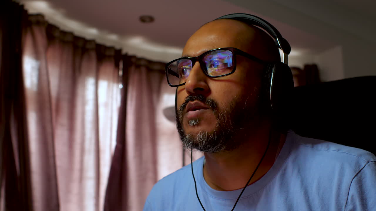 Sørasisk mann med briller som tar på seg hodetelefoner og lytter til musikk innendørs