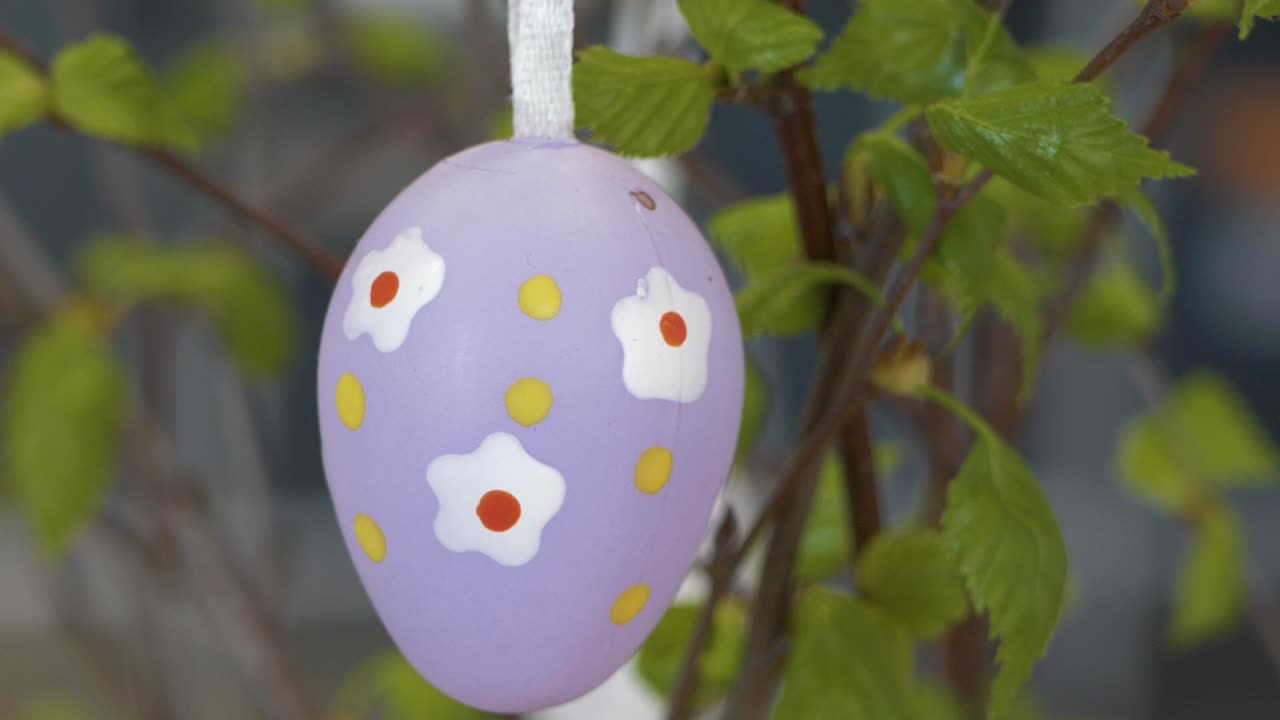 An artificial Easter egg hung on a birch branch in a vase