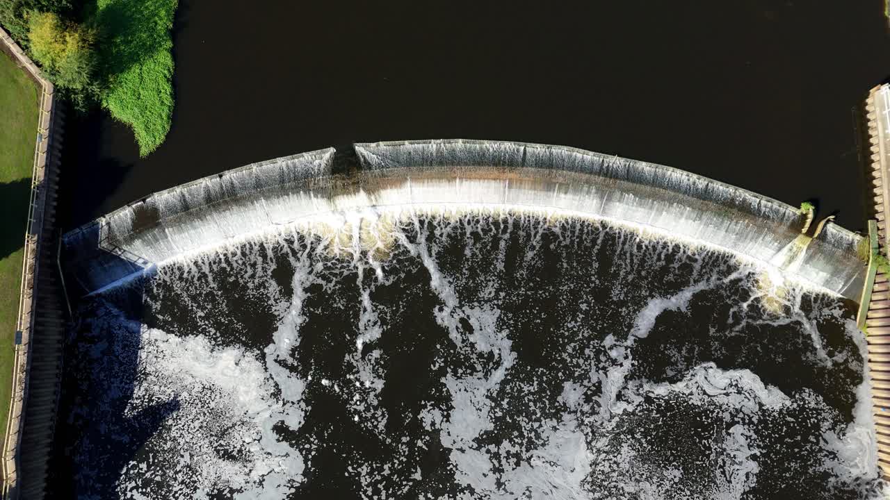 Aerial drone shot of Ferrybridge hydroelectric power plant with huge weir on River Aire and industrial factories along banks Yorkshire UK summer landscape