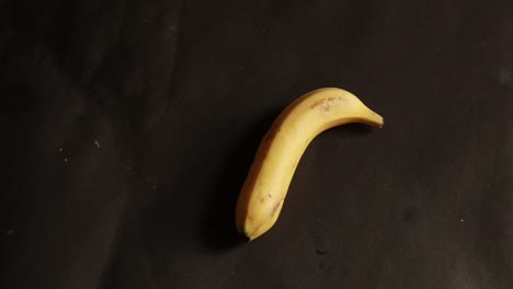 바나나는 검은 배경에 고립 된 원으로 회전