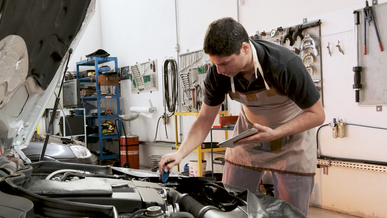 mecánico revisando el auto, tomando notas y abriendo la tapa de la botella del lavaparabrisas