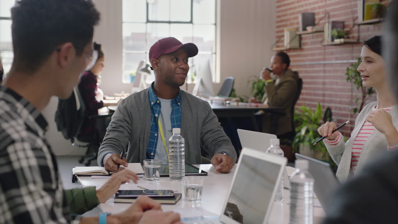 reunión de equipo creativo empresario afroamericano gerente compartiendo comentarios sobre el proyecto discutiendo estrategia colegas colaborando en una oficina moderna ocupada