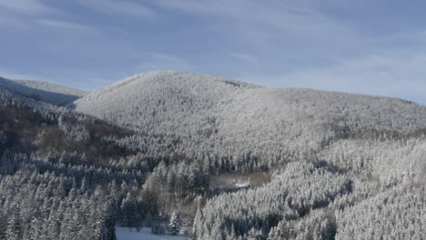 Rising-Aerial-Shot-Of-A-Scenic-Winter-Landscape,-Mountains-And-Forest-Covered-In-White-Snow