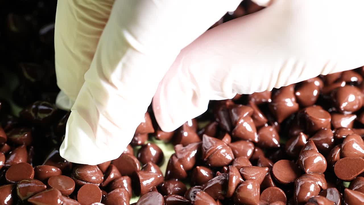 manos con guantes clasificando trozos de chocolate en una superficie