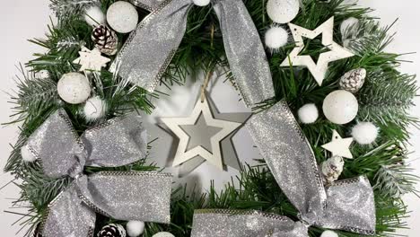 corona de navidad que decora la puerta principal para las fiestas hechas de abeto, arcos de plata, estrellas y bolas de navidad aisladas sobre un fondo blanco
