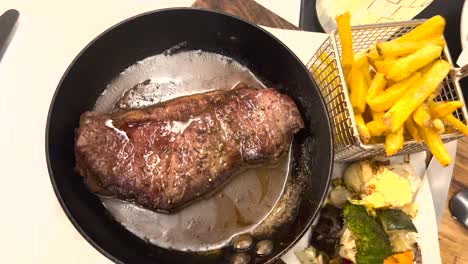 a succulent grilled beef steak, served with crispy french fries, a colorful medley of vegetables, and a runny fried egg