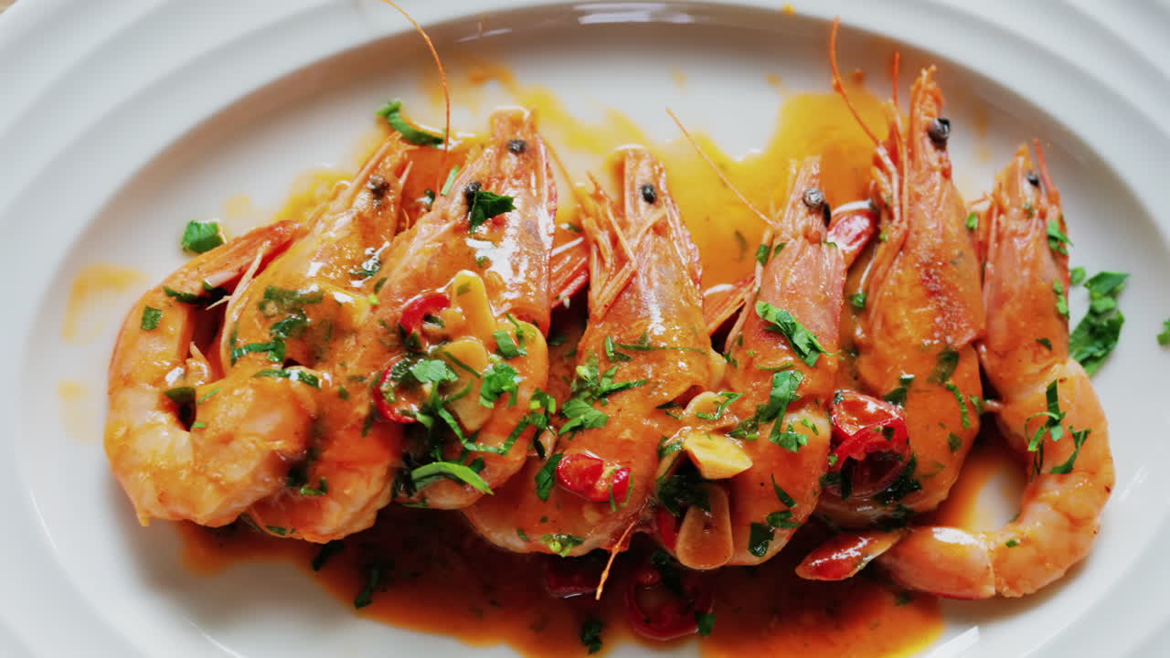 Garlic prawns in a rich sauce topped with herbs on a white plate