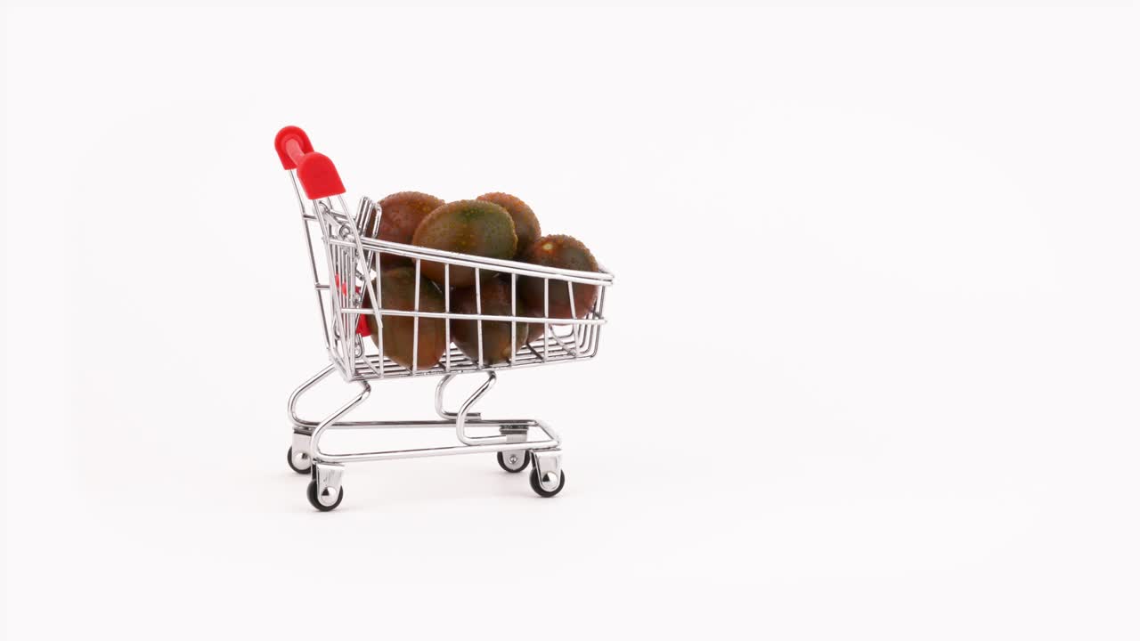 Sich bewegender Einkaufswagen, gefüllt mit einem Haufen schwarzer Kirschtomaten mit Wassertropfen. Isoliert auf weißem Hintergrund. Nahaufnahme. Makro.