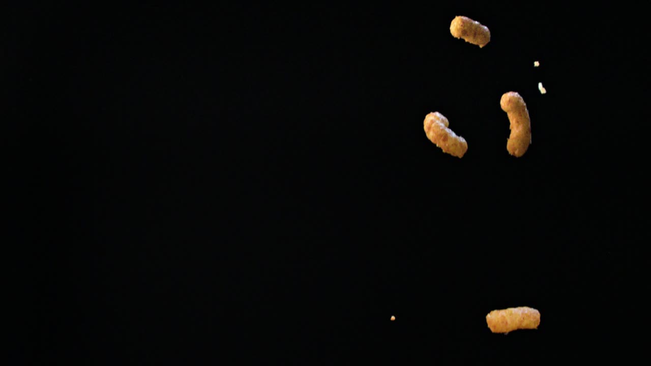 Bastoncini di mais che cadono su uno sfondo nero pece