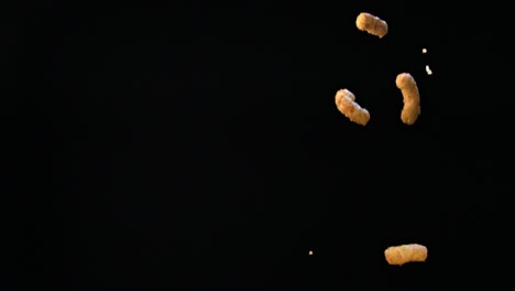 corn sticks falling against a pitch black background