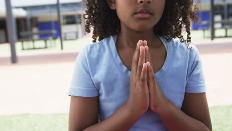 chica biracial de azul, manos juntas, se centra en la escuela