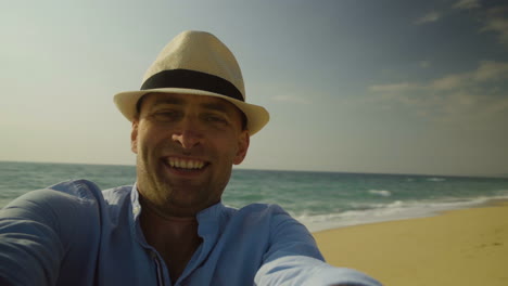 handsome man in hat turning around on beach