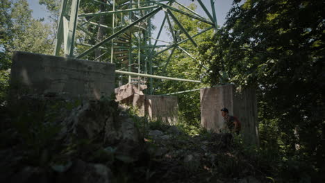 Man-approached-a-green-lookout-tower-on-moutain-Boč,-pausing-and-looking-at-the-top-of-a-tower