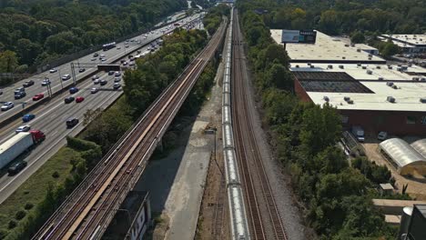 toma aérea de arriba hacia abajo de una autopista concurrida con un tren durante un día soleado en el área suburbana de atlanta