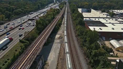 aerial top down shot of busy highway with train during sunny day in suburb area of atlanta