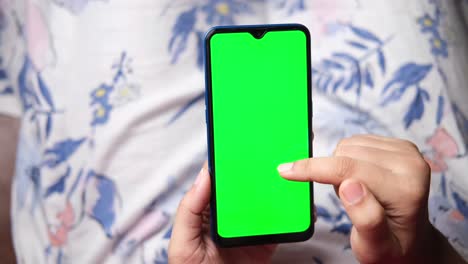 persona que sostiene un teléfono inteligente con una pantalla verde