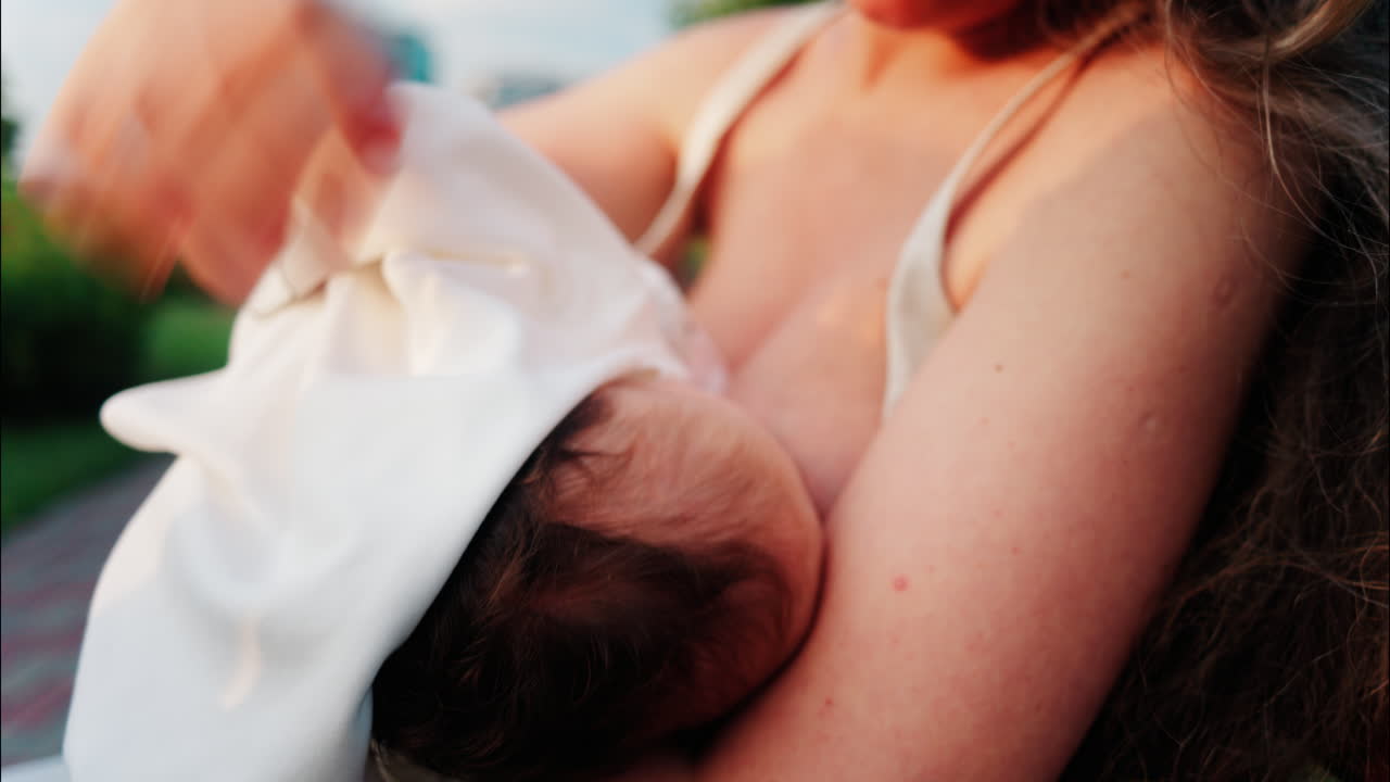 Close up of a mother holding her newborn in her arms outdoors during sunset