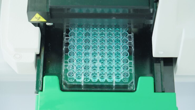 Primo piano di una macchina per attrezzature scientifiche che riempie una micropiastra in laboratorio, 4K