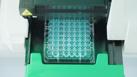 close up of scientific equipment machine filling microplate in laboratory, 4k