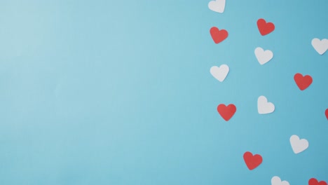 multiple red and pink paper hearts at valentine's day on blue background