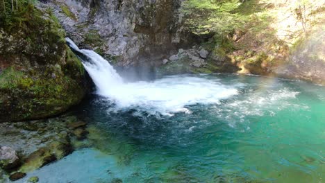 drone view in albania in the alps circling in front of a waterfall surrounded by the rocky and green mountain over blue pool in theth