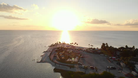 Aerial-pullback,-immaculate-white-beach-with-sunrise-over-water